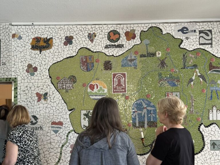 Besuchsgruppe vor einer großen Wandkarte der Altmark aus Keramikmosaik